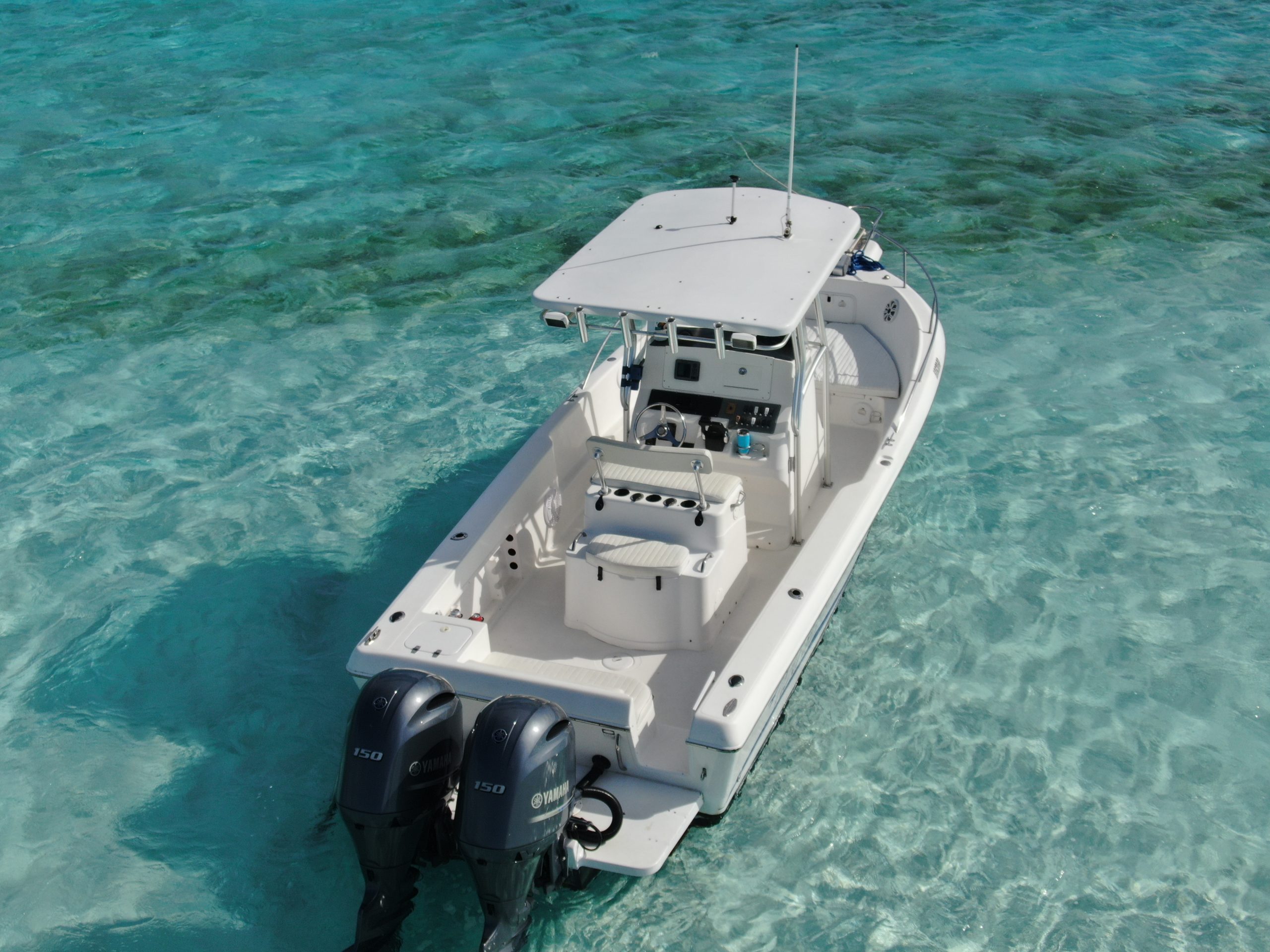 A white boat with a motor in the clear blue water, perfect for Staniel Cay Boating.