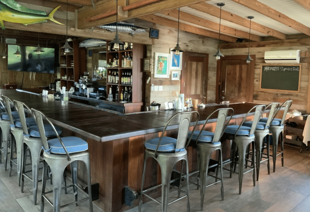 A bar with several stools and a wooden ceiling, located in the stunning Staniel Cay in the Bahamas.