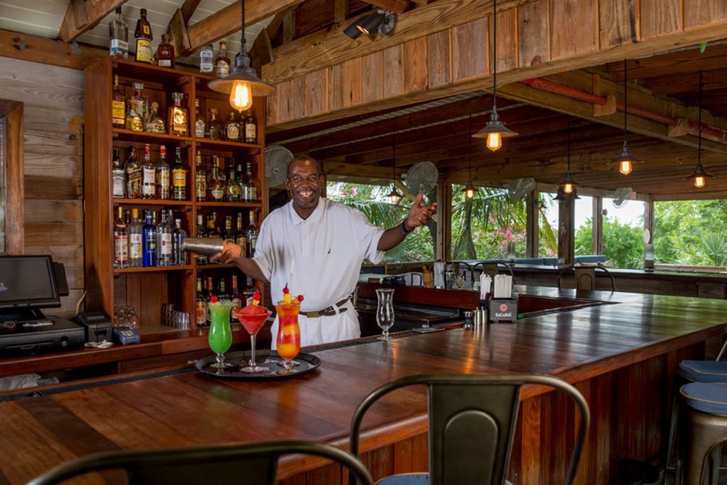 A bartender standing behind a wooden bar at Staniel Cay Bahamas.