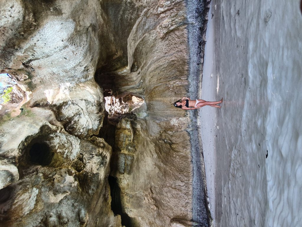 A woman in a bikini exploring a cave at Staniel Cay in the Bahamas.