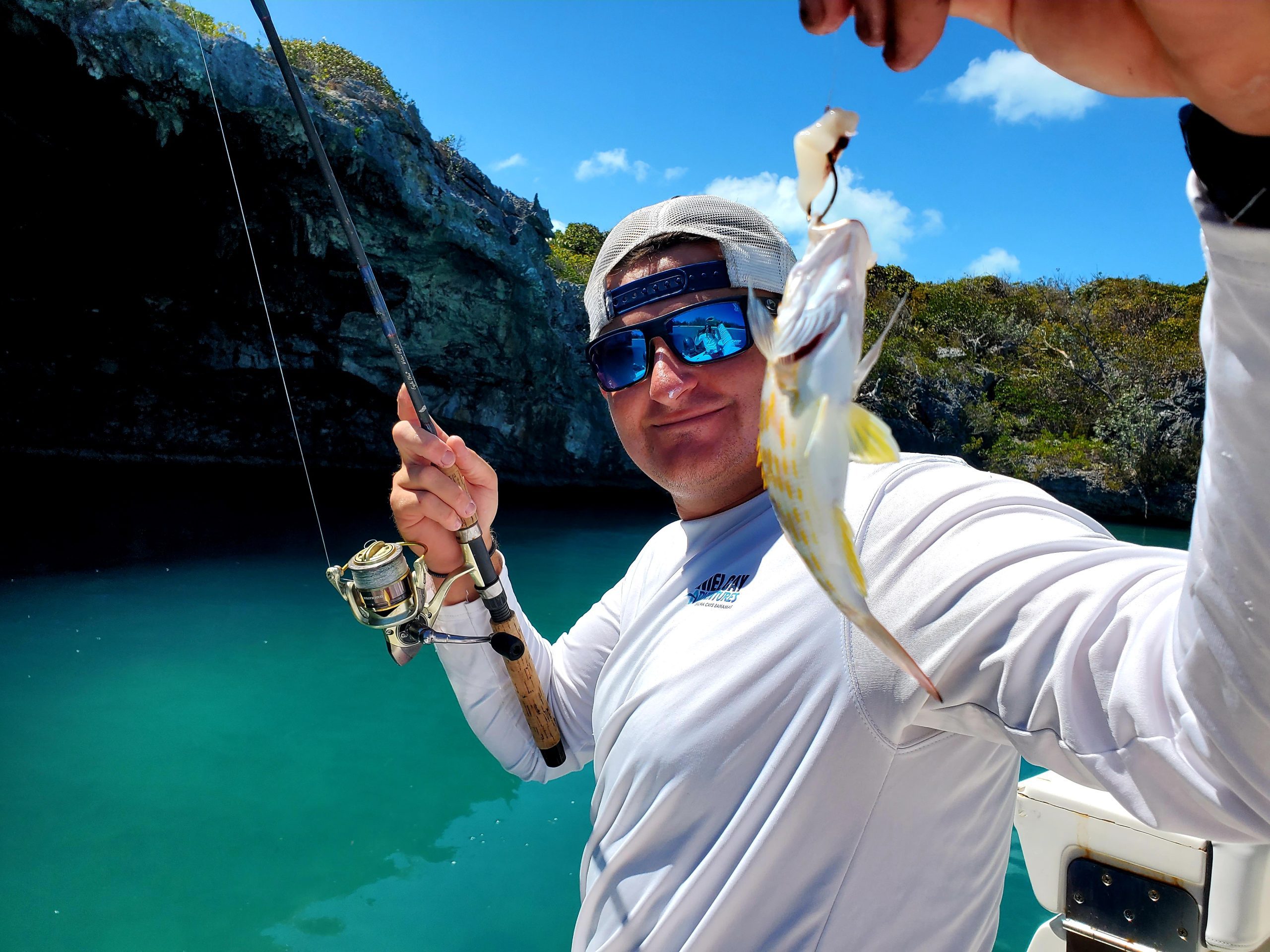 A man holding up a fish while scuba diving in the Exuma Cays, Bahamas.