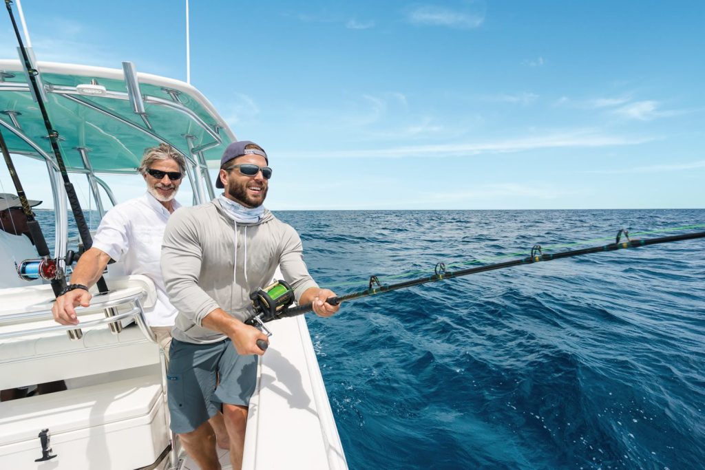 Two men on a boat in the ocean, enjoying a fishing trip in Exuma Cays, Bahamas.