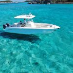 A white boat is floating in the clear blue water near the Exuma Cays Bahamas.