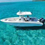 A white boat is floating in the clear blue water off the coast of Staniel Cay in Exuma Cays, Bahamas.