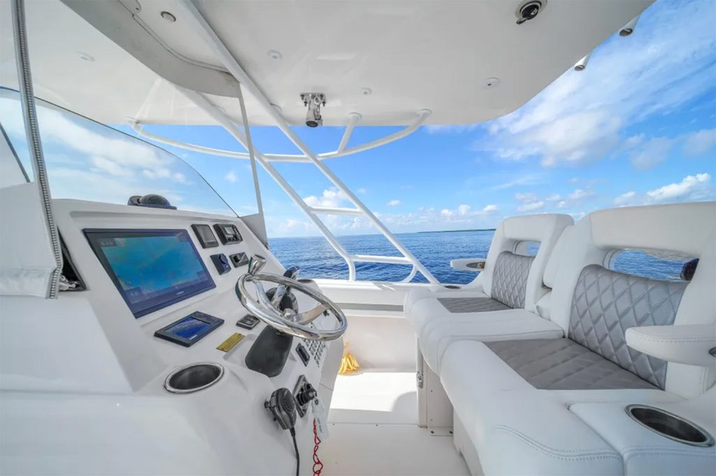 Staniel Cay, Exuma Bahamas View of a boat's helm with steering wheel, navigation screens, and white cushioned seats, set against a backdrop of blue ocean and sky. Swimming Pigs Tours, Fishing and more!