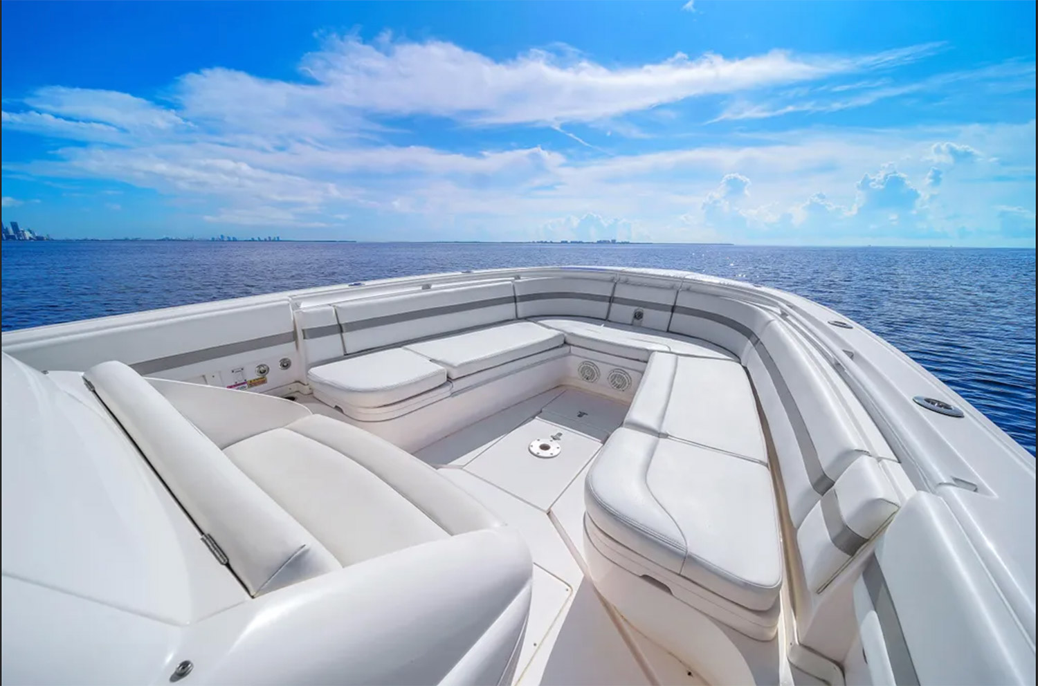 Staniel Cay, Exuma Bahamas White cushioned seating area on the deck of a boat, with calm blue ocean and a partly cloudy sky visible in the background. Swimming Pigs Tours, Fishing and more!