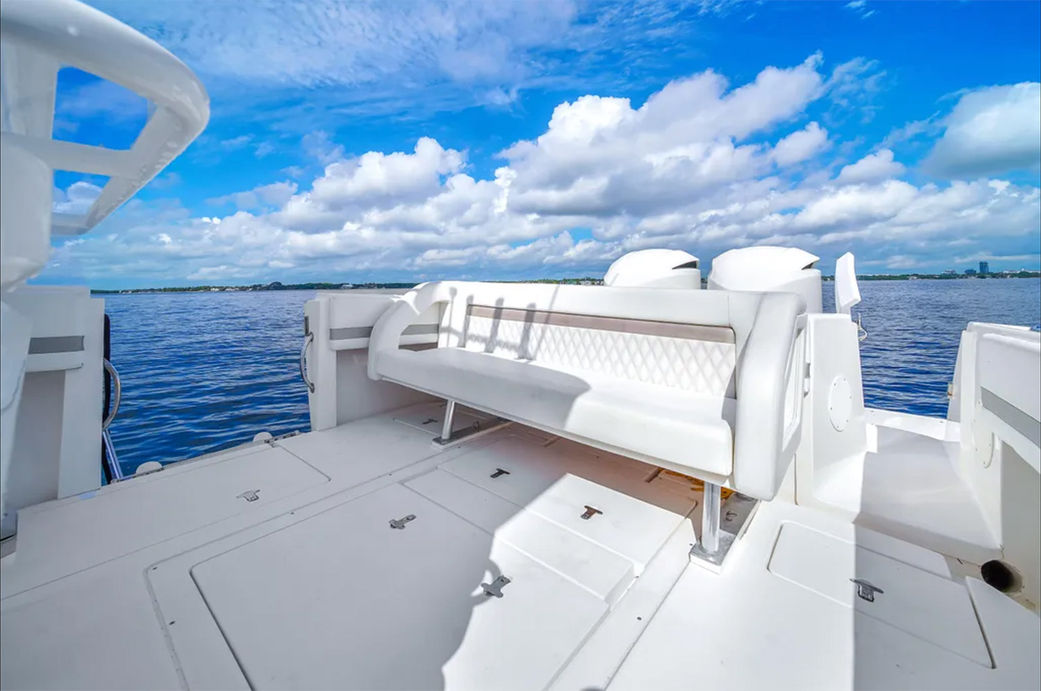 Staniel Cay, Exuma Bahamas White bench seating on the deck of a boat with surrounding blue water and a partly cloudy sky in the background. Swimming Pigs Tours, Fishing and more!