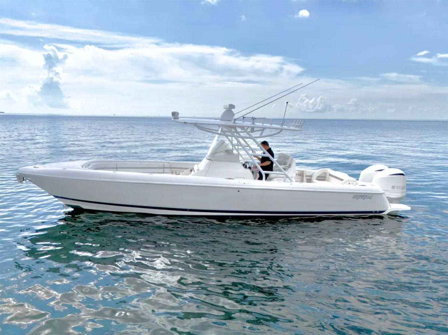 Staniel Cay, Exuma Bahamas A white powerboat with two outboard motors floats on calm water under a partly cloudy sky; a person stands at the helm. Swimming Pigs Tours, Fishing and more!