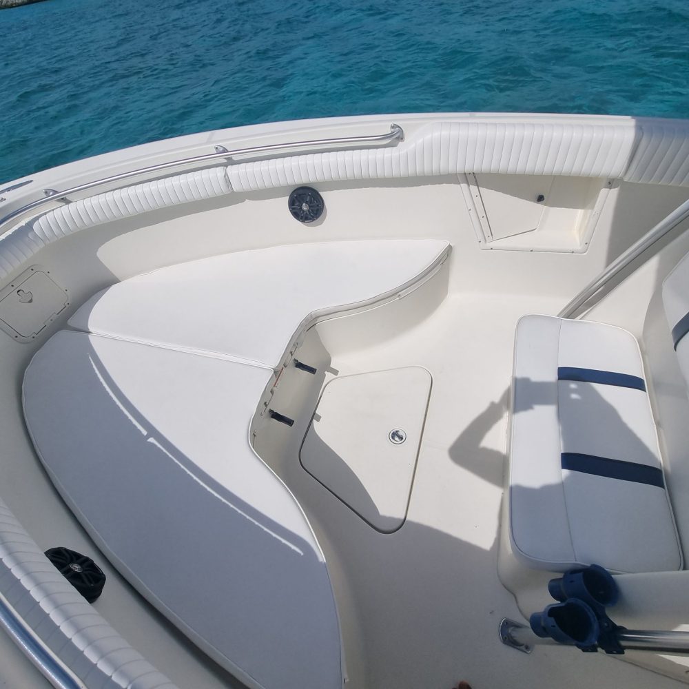 Staniel Cay, Exuma Bahamas Seating area at the front of a boat with white cushions and blue accents, set against a backdrop of clear blue water.