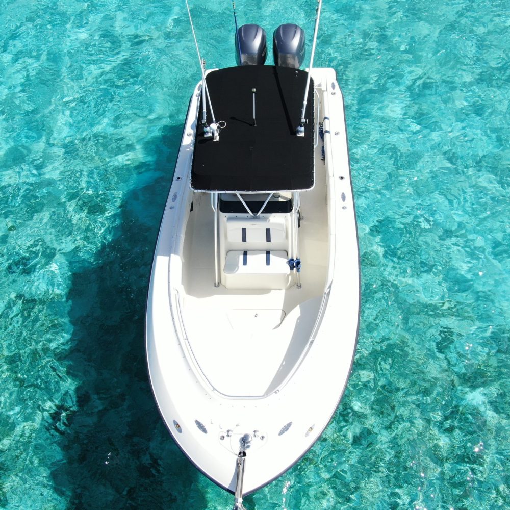 Staniel Cay, Exuma Bahamas A small white motorboat with a black canopy floats on clear turquoise water.