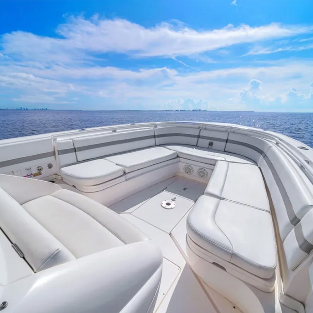 Staniel Cay, Exuma Bahamas White cushioned seating area on the deck of a boat, with calm blue ocean and a partly cloudy sky visible in the background. Swimming Pigs Tours, Fishing and more!