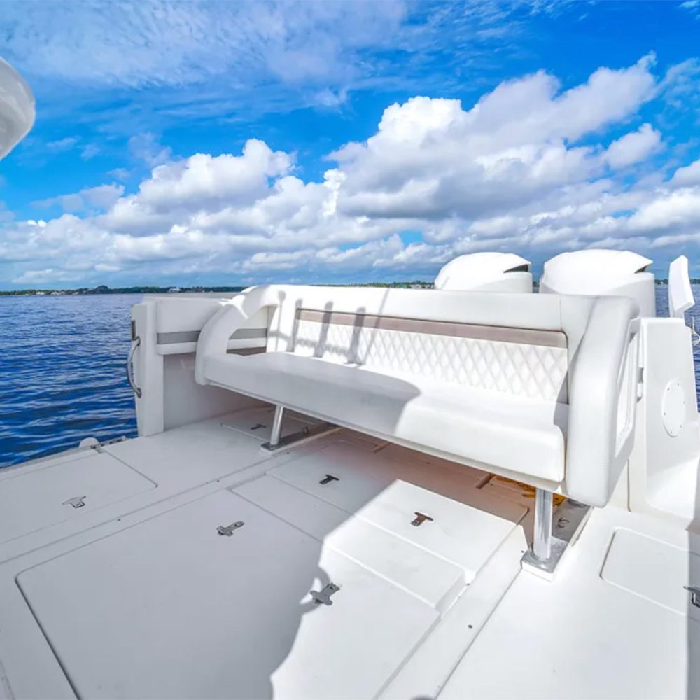 Staniel Cay, Exuma Bahamas White bench seating on the deck of a boat with surrounding blue water and a partly cloudy sky in the background. Swimming Pigs Tours, Fishing and more!