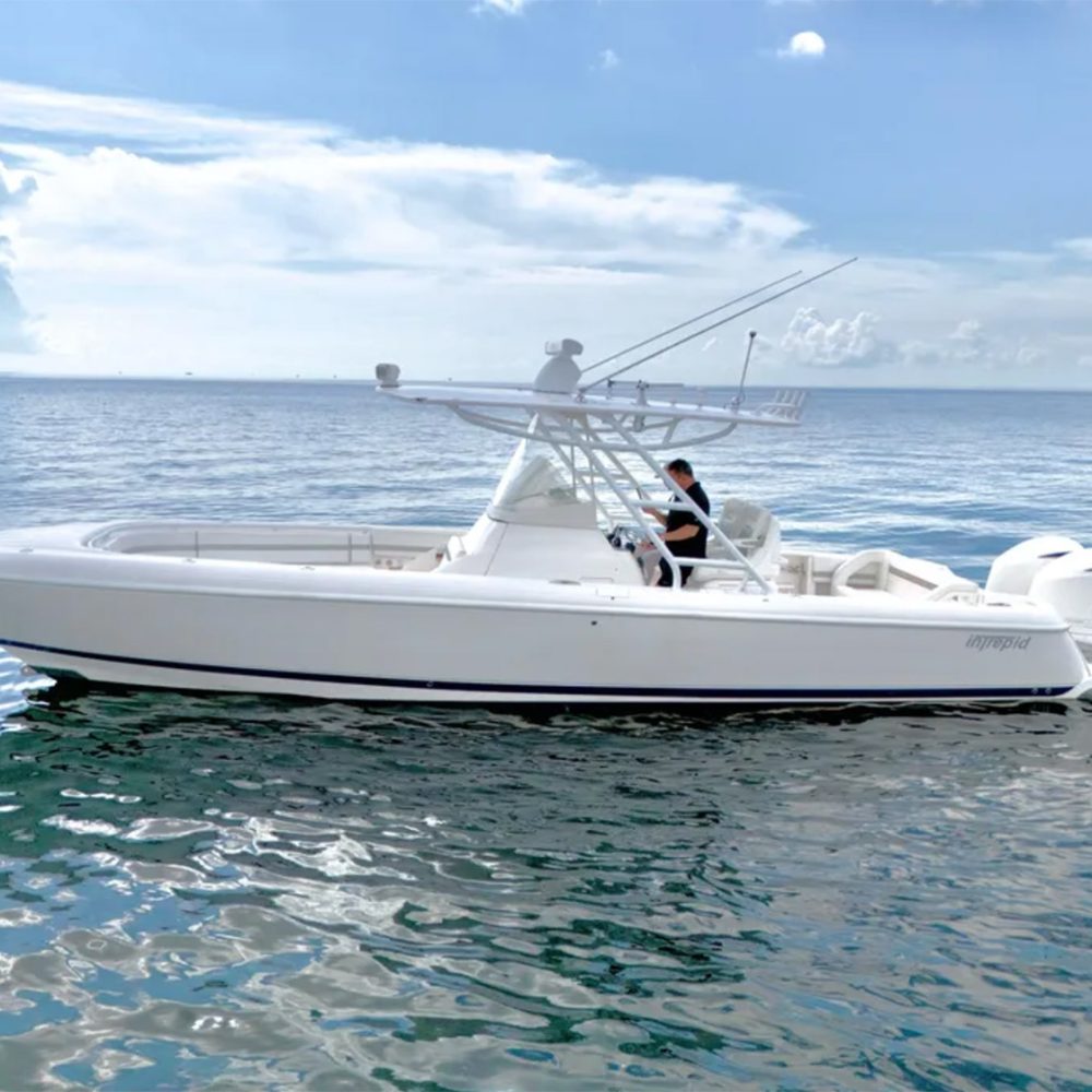 Staniel Cay, Exuma Bahamas A white powerboat with two outboard motors floats on calm water under a partly cloudy sky; a person stands at the helm. Swimming Pigs Tours, Fishing and more!