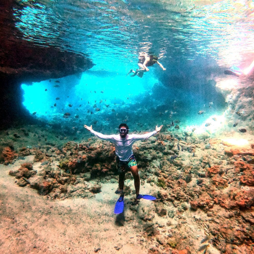 Staniel Cay, Exuma Bahamas Person snorkeling in clear blue water, surrounded by underwater rock formations and fish.