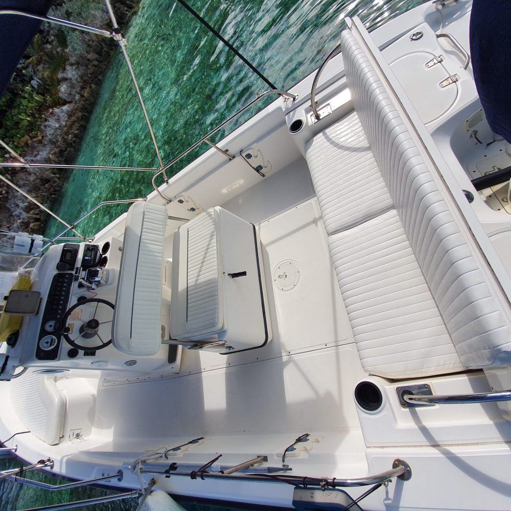 Staniel Cay, Exuma Bahamas The image shows the interior of a small white boat with cushioned seating and a steering console, anchored on clear turquoise water.