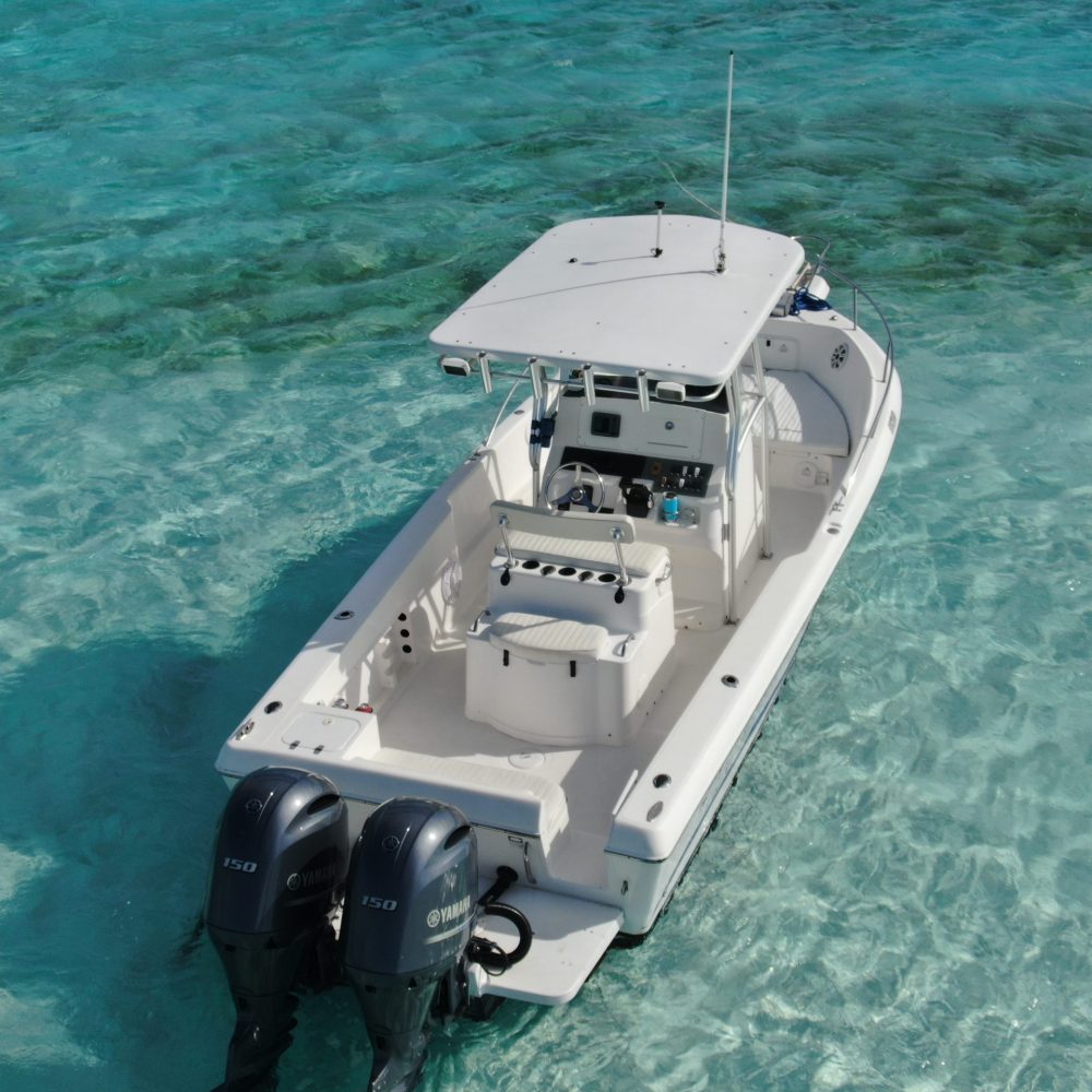 Staniel Cay, Exuma Bahamas A white motorboat with two engines floats on clear turquoise water, with no people on board.