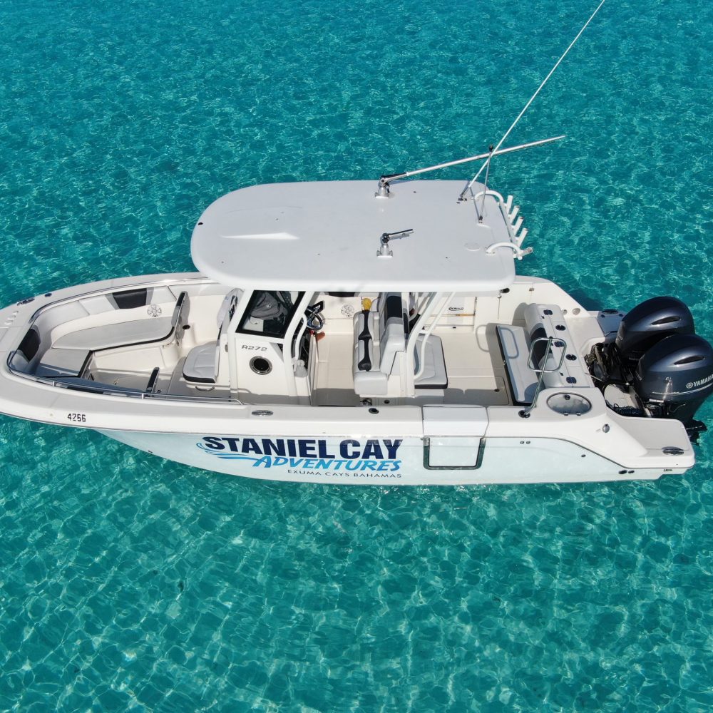 Staniel Cay, Exuma Bahamas A white motorboat labeled "Staniel Cay Adventures" floats on clear turquoise water, with two outboard engines.