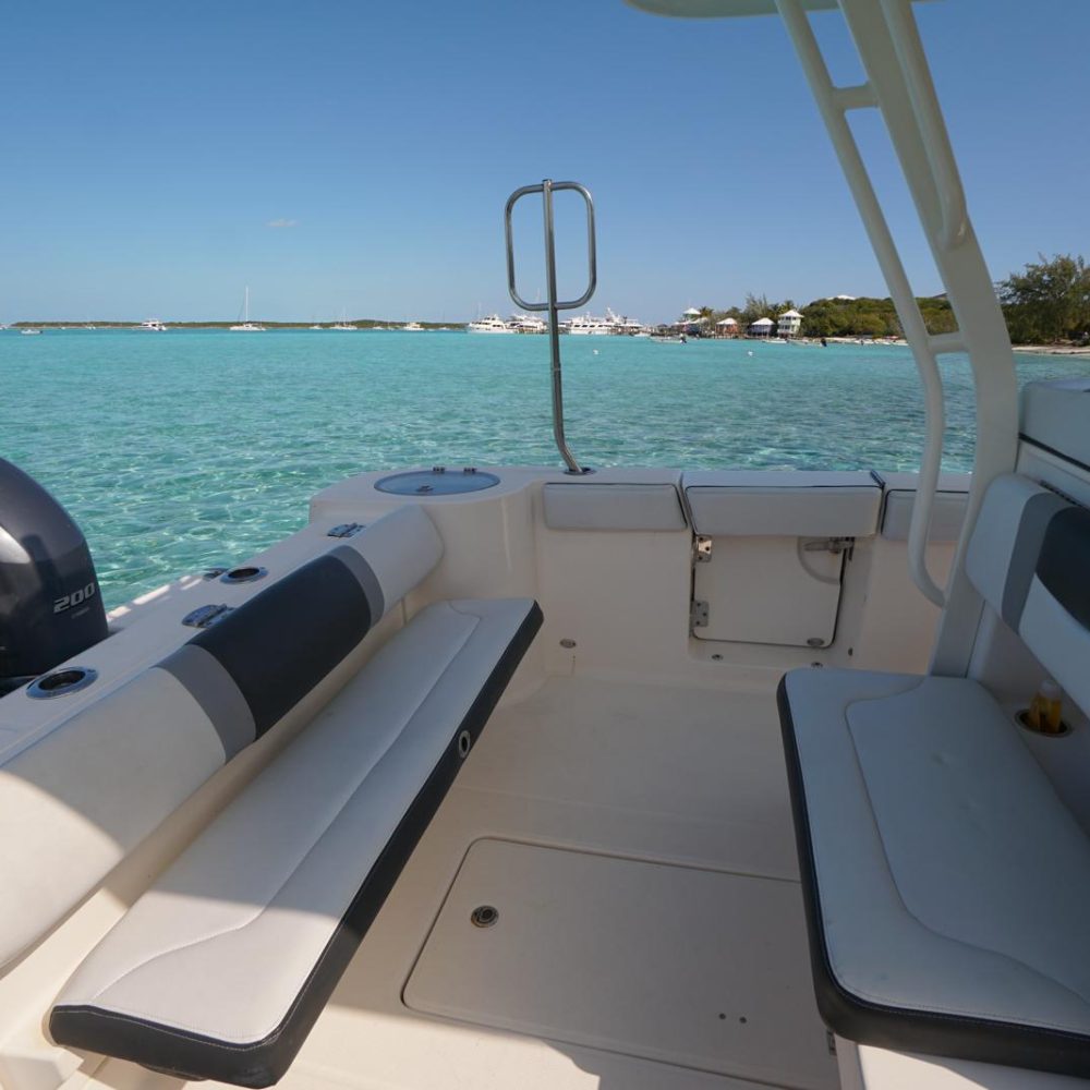 Staniel Cay, Exuma Bahamas View from a boat's cabin showing seating and outboard motors, with clear turquoise water and several other boats in the distance on a sunny day.