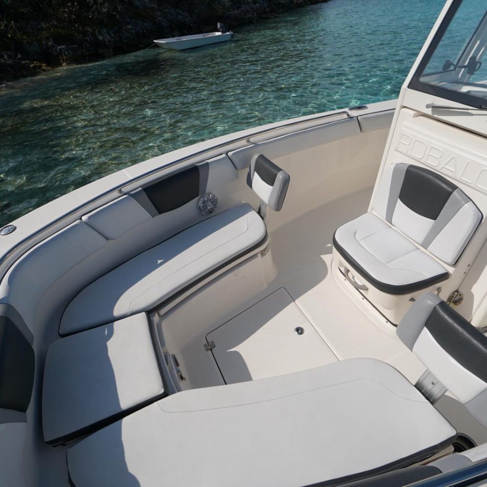 Staniel Cay, Exuma Bahamas Interior view of a boat with white and gray seating, surrounded by clear blue water. A small boat is visible in the background.