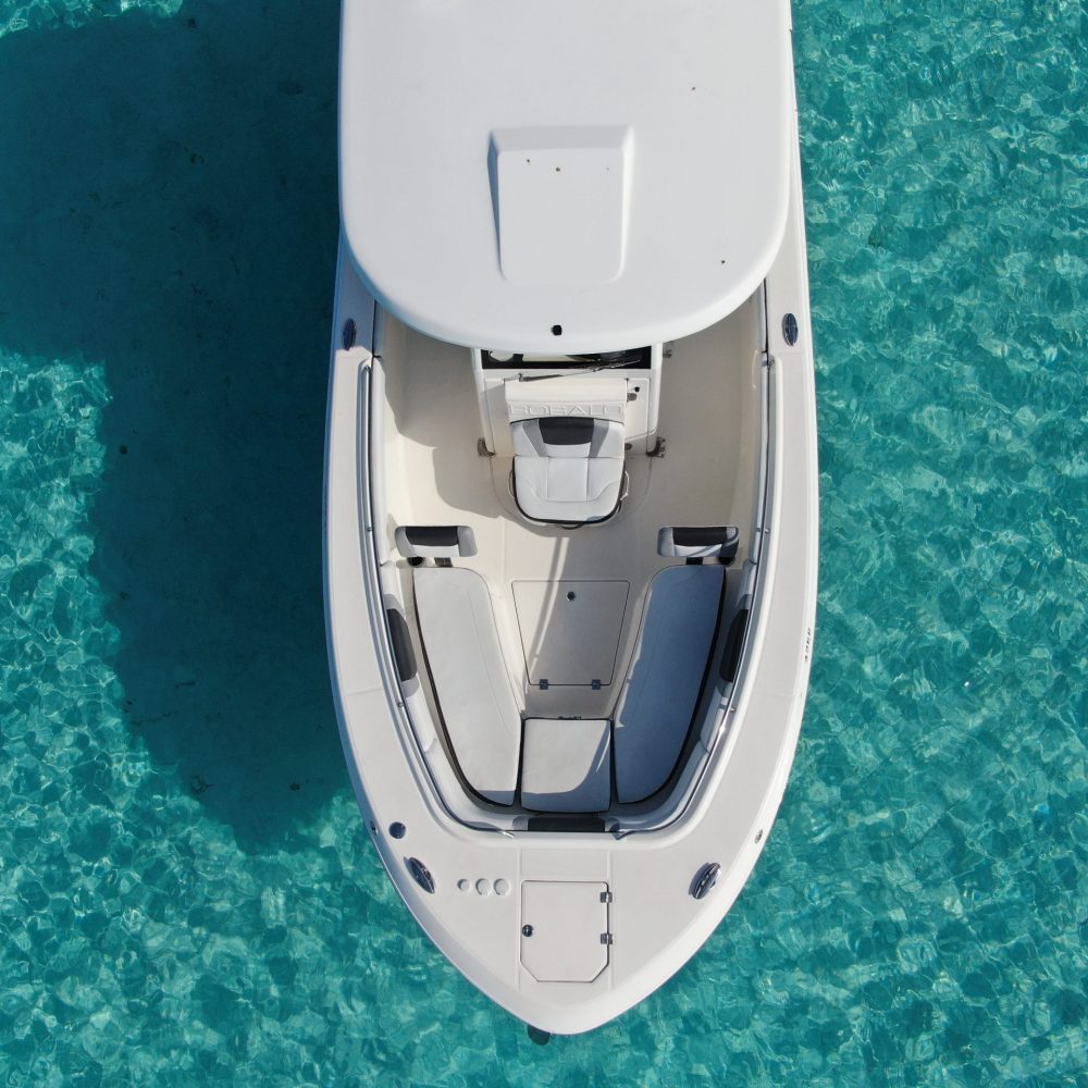 Staniel Cay, Exuma Bahamas Aerial view of a white boat with an enclosed cabin, floating on clear turquoise water.